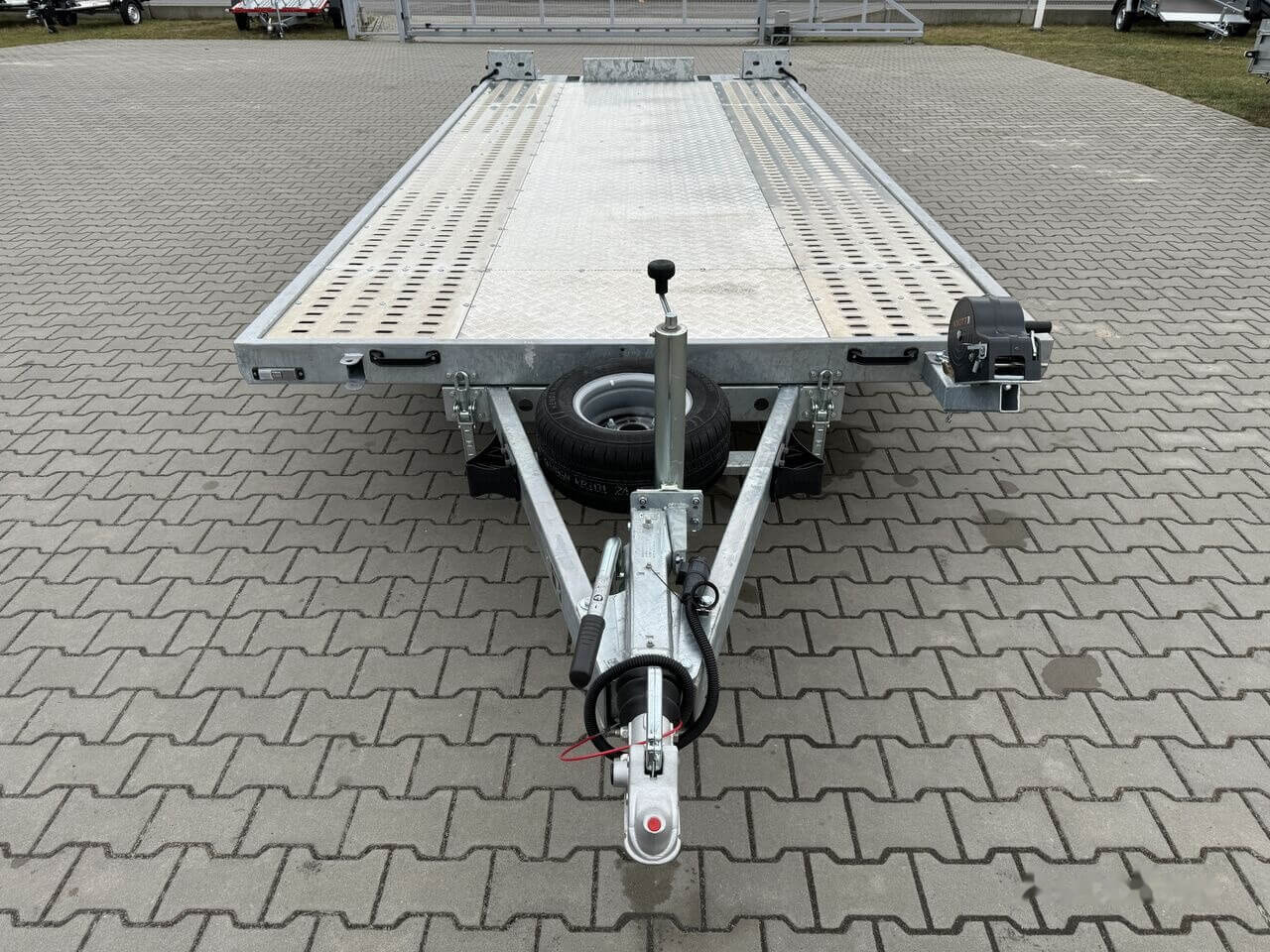 Remorcă pentru transport auto parcată pe pavaj.