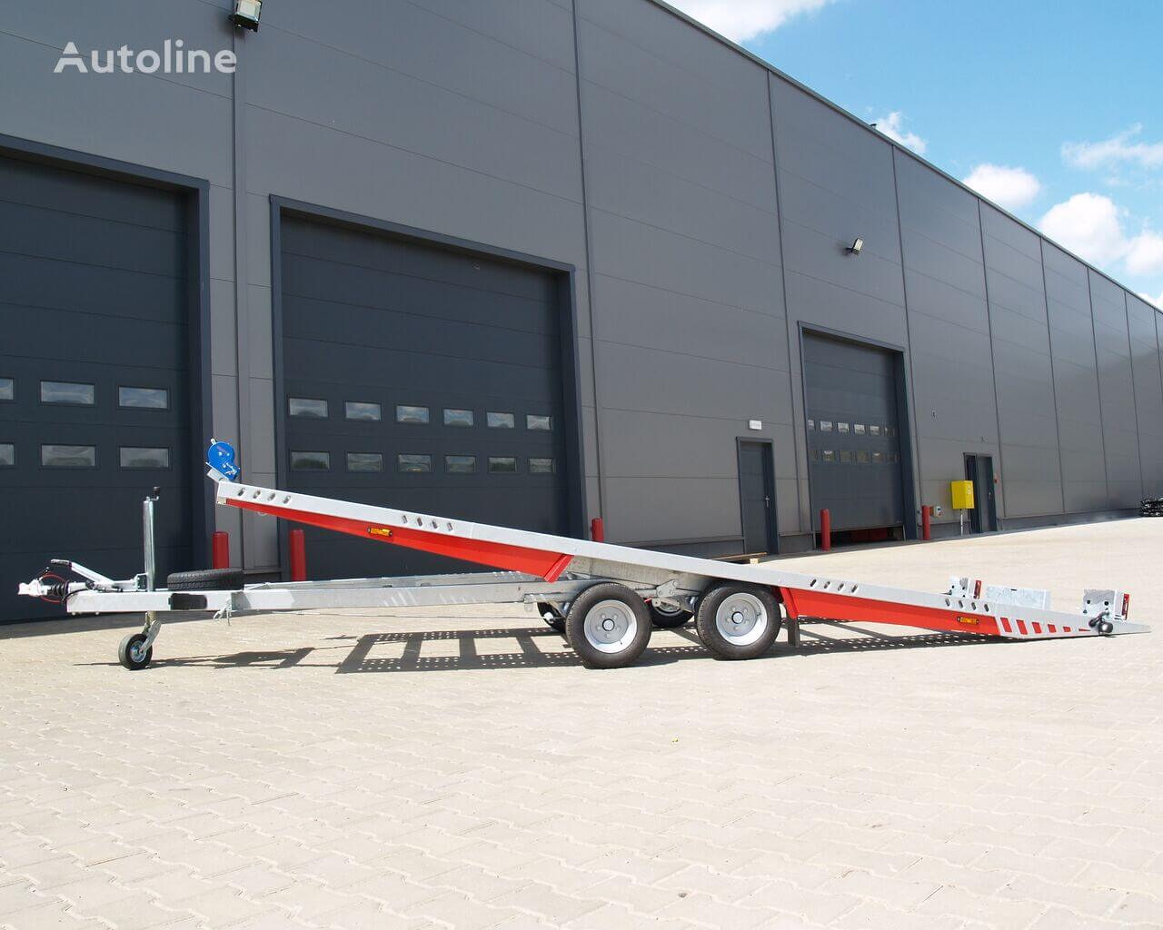 Remorcă auto în fața unui depozit industrial.